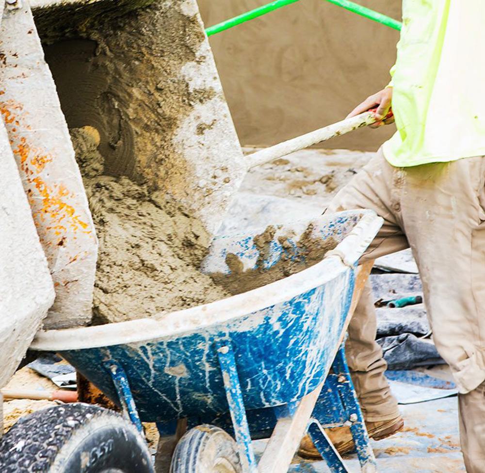 worker with cement in wheel barrel